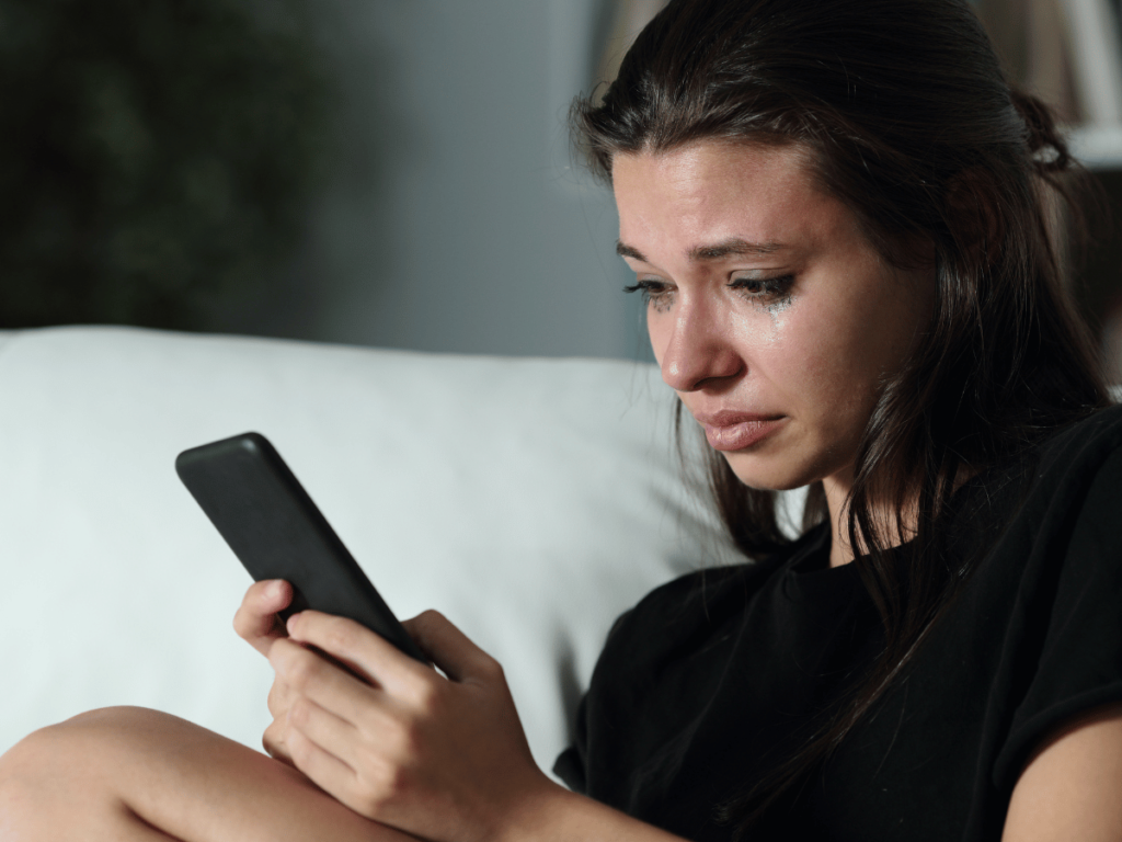 Image of a white woman crying while on her phone for a blog about digital detox